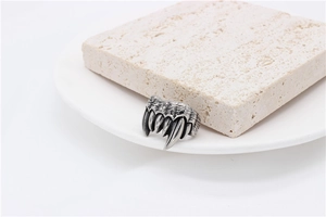 Detailed view of vintage silver monster claw fangs ring on textured stone and ceramic