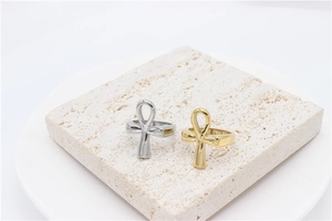 Detailed macro view of gold and silver Ankh cross rings on a textured stone display