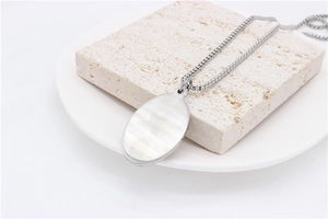 Macro shot of oval steel pendant back showing brushed metal texture on a stone