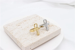Detail view of gold and silver Ankh cross open rings on a minimalist stone display