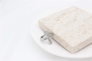 Macro view of polished silver Ankh cross ring leaning on natural white stone texture