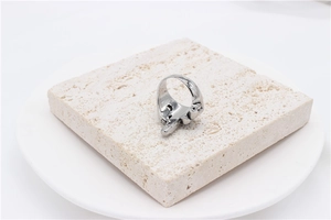 Detailed close-up of a silver punk rocker hand gesture ring on a white textured stone base