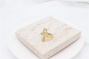 Close-up of golden Ankh cross ring on a minimalist stone pedestal display