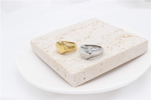 Polished heart signet rings in gold and silver finish on elegant white stone background