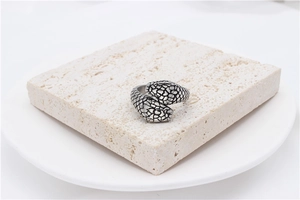 Macro shot of double snake head steel ring with detailed scales on a stone tile