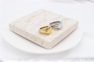 Close-up of polished gold and silver chunky heart rings on a textured stone stand