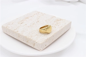Detailed view of polished golden heart signet ring on natural stone texture pedestal