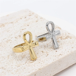Polished gold and silver Ankh cross rings displayed on a textured stone base