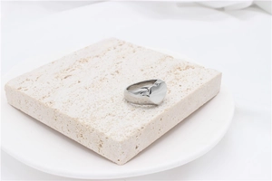 Macro view of minimalist silver heart ring on stone pedestal with polished finish