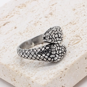 Adjustable double snake head titanium steel ring with vintage scale texture on stone background