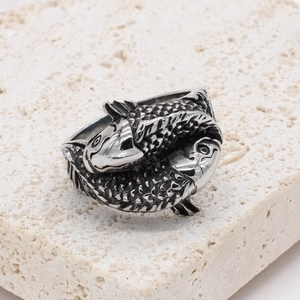 Vintage koi carp titanium steel ring with intricate fish scale textures on travertine stone