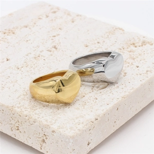 Minimalist heart-shaped signet rings in polished gold and silver on natural stone