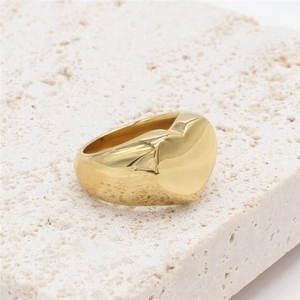 Minimalist wide band ring with 3D heart shape in golden finish on stone background