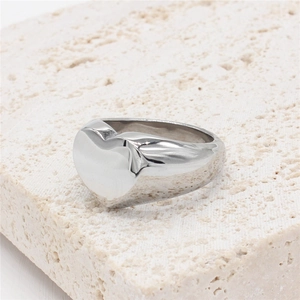 Minimalist silver heart ring with polished wide band shown on a natural stone base