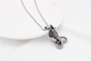 Detail of vintage cobra pendant with square pearl chain on a minimalist white backdrop