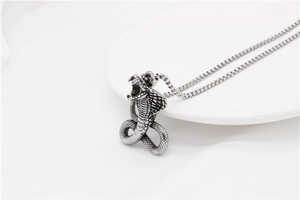 Macro shot of cobra pendant with detailed scales and vintage silver finish on box chain