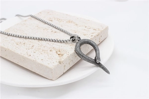 Macro detail of vintage silver snake pendant with realistic scale texture on box chain