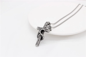 Dettaglio del ciondolo a croce con serpente avvolto su catena in acciaio inox vintage