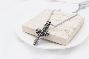 Close-up of gothic stainless steel pendant with dagger, cross, and skull details on a chain