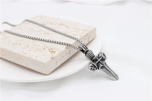 Detail of gothic sword cross pendant with skull design on vintage stainless steel box chain