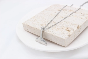 Collier avec pendentif queue de baleine poli sur un fond en pierre naturelle texturée