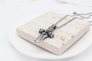 Macro detail of vintage gothic cross sword pendant with skull design on stone base