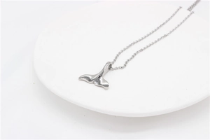 Vue détaillée du pendentif queue de baleine poli et de sa chaîne à maillons en acier