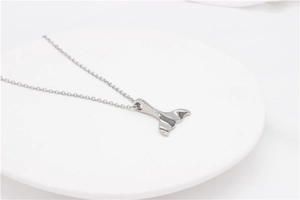 Gros plan détaillé du pendentif queue de baleine poli sur une chaîne minimaliste en acier