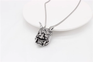 Macro shot of retro silver Hannya mask pendant with punk style details on a metal chain