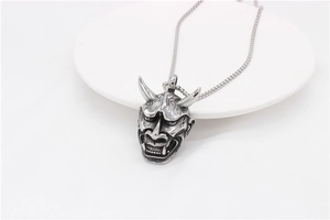 Detailed close-up of retro silver Hannya mask pendant on a box chain necklace