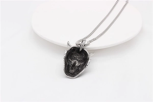 Close-up of vintage silver demon mask pendant with intricate blackened steel details