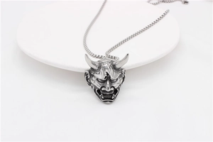 Detailed view of carved vintage silver Hannya mask pendant on a stainless steel box chain