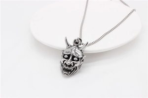 Detail shot of vintage silver Hannya mask pendant with oxidized steel finish and box chain