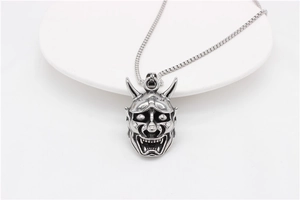 Detailed close-up of a silver-tone Hannya mask pendant with intricate demon carvings