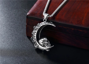 Close-up of gothic crescent moon pendant with skull detail on a vintage chain