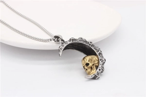 Macro shot of silver crescent moon pendant with gold skull on a white jewelry plate
