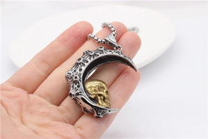 Macro detail of gothic stainless steel crescent moon pendant with golden skull on ball chain