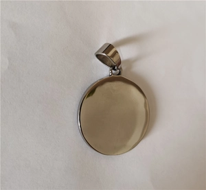 Close-up of a minimalist round polished silver steel viking pendant on white paper