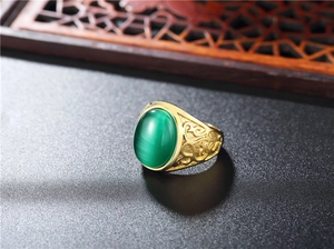 Close-up of vintage gold titanium ring featuring a green cat-eye gemstone and floral carving
