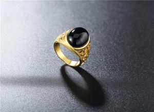 Detail view of gold-plated signet ring with oval black onyx stone and filigree carving