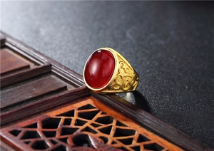 Macro view of vintage gold ring featuring a large oval red gemstone and filigree details