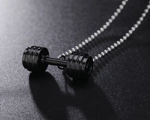 Vue macro latérale d'un pendentif haltère noir avec chaîne à billes sur surface mate