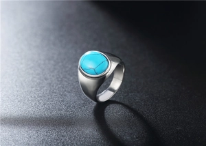 Macro shot of polished oval turquoise stone with black veins on titanium steel ring