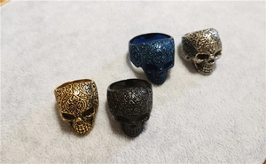 Vista dettagliata di quattro anelli teschio punk retrò in oro, nero, blu e argento
