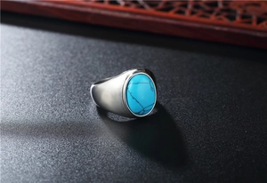 Macro detail of oval turquoise stone with black veins on heavy silver steel ring band