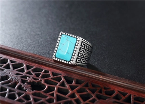 Dettaglio dell'anello vintage da uomo in acciaio con pietra turchese e motivo greco