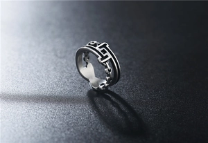 Macro shot of silver chain ring with geometric H pattern and black enamel details