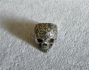 Dettaglio dell'anello teschio punk vintage con incisioni barocche e finitura argento