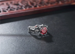 Macro shot of gothic skull ring in vintage steel finish with a large faceted red gemstone