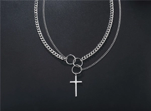 Detail of silver layered cross necklace with Cuban chain and minimalist pendants on black